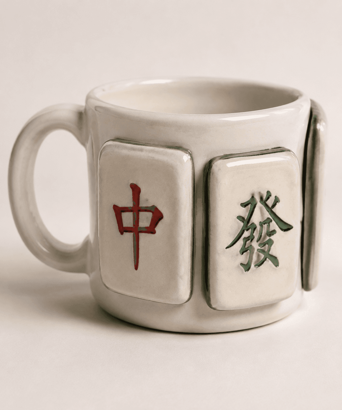 Handmade ceramic mug with red and green mahjong dragon tiles applied to the side
