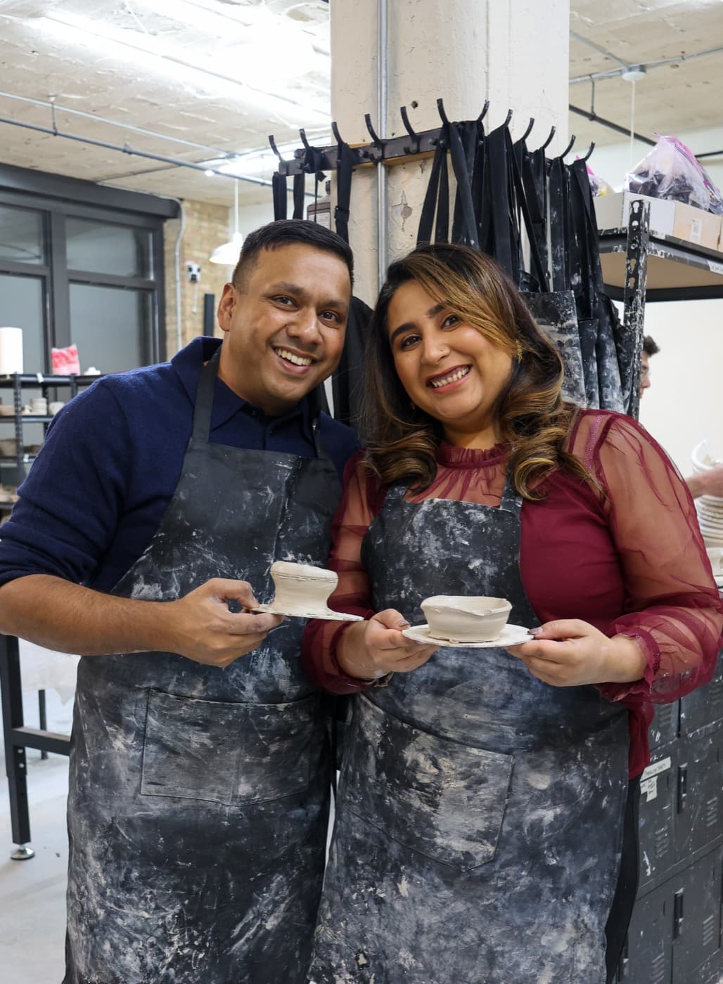 A couple at the studio, smiling, holding the pieces they made together