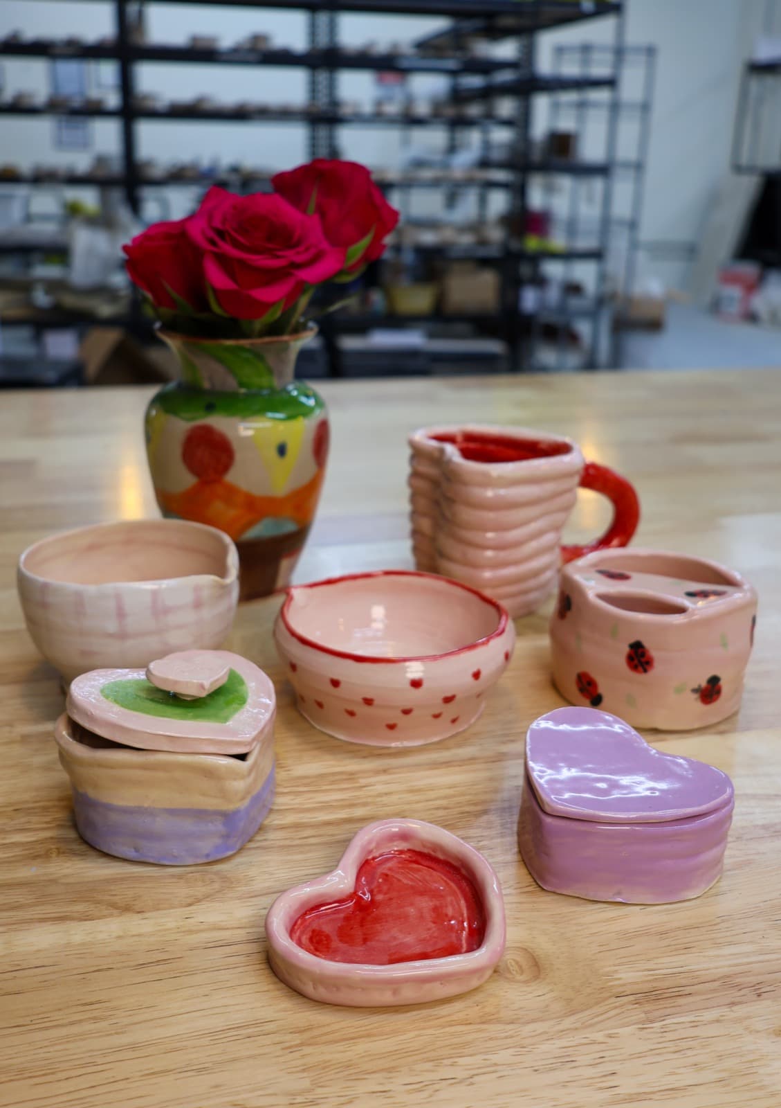 Finished pottery pieces from a Valentine's wheel class: bowls, a mug, a vase of roses