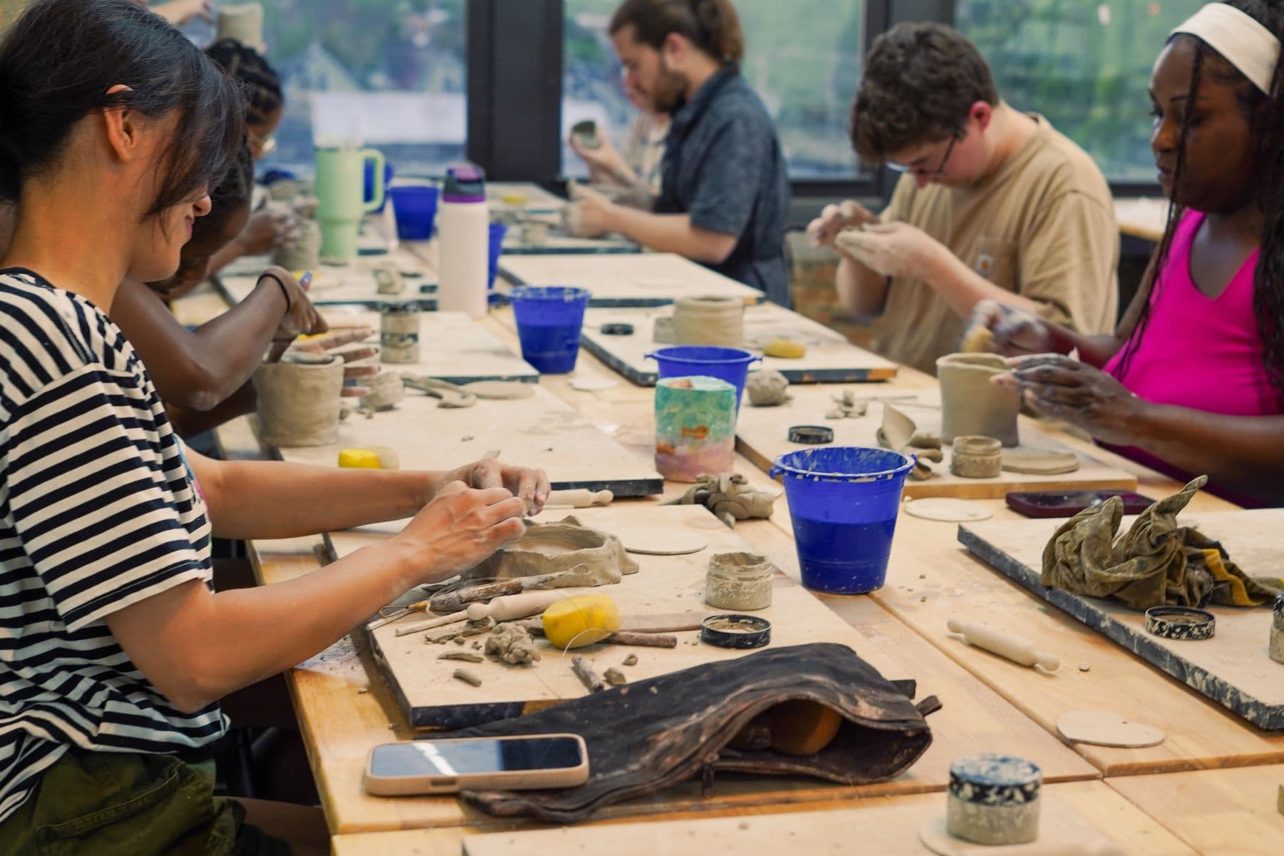 A pottery class working at a communal studio table