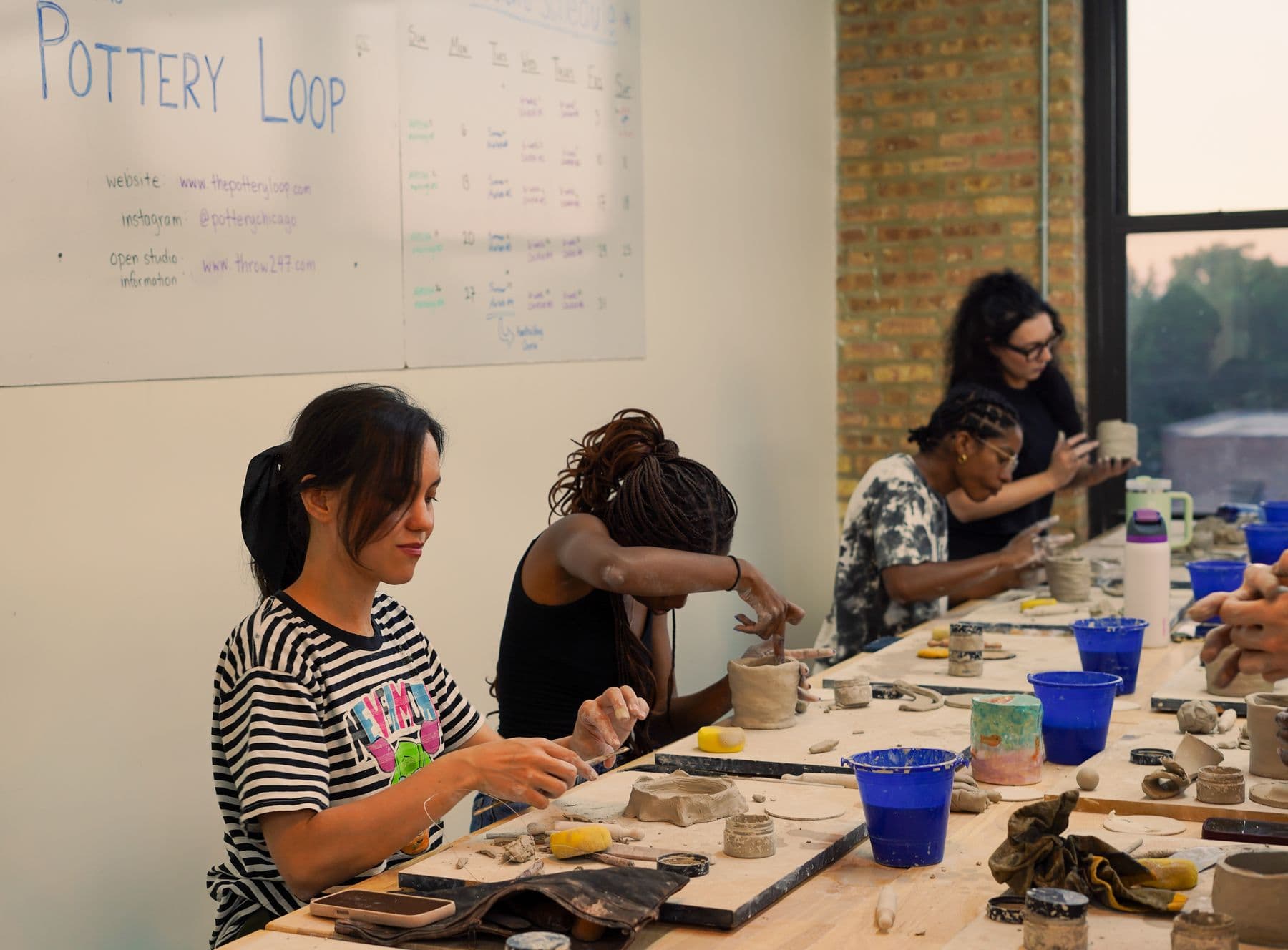 A full pottery class at The Pottery Loop with the studio whiteboard in view
