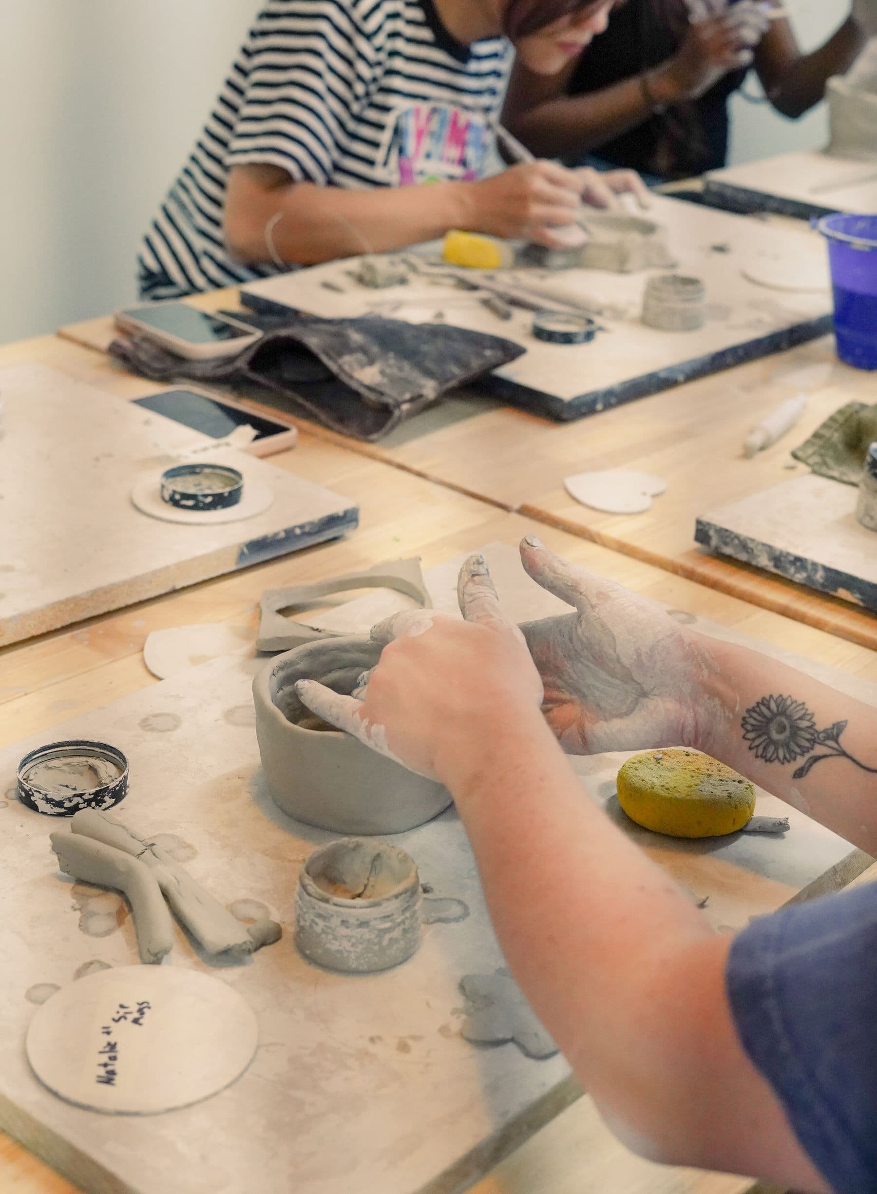 Hands coil-building a clay vessel