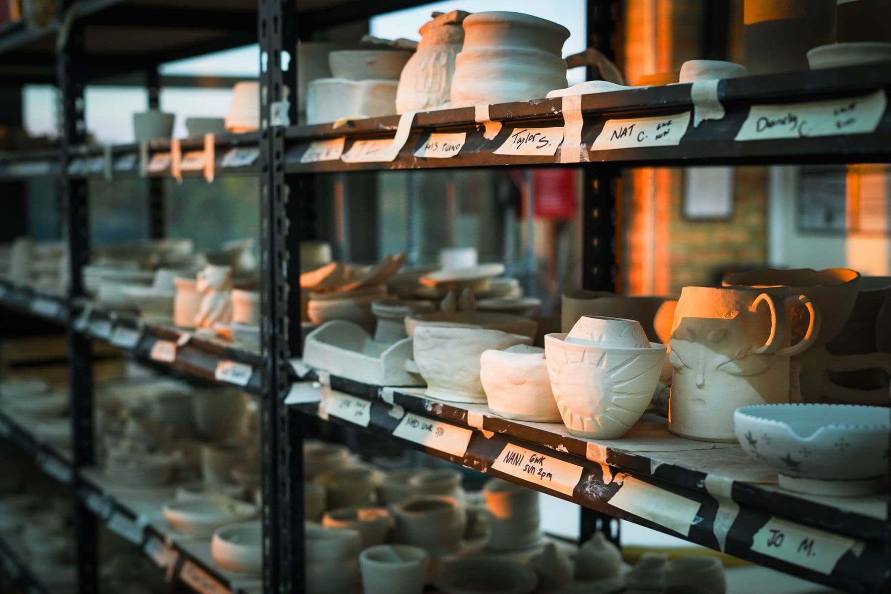 Handmade pottery drying on studio shelves at golden hour