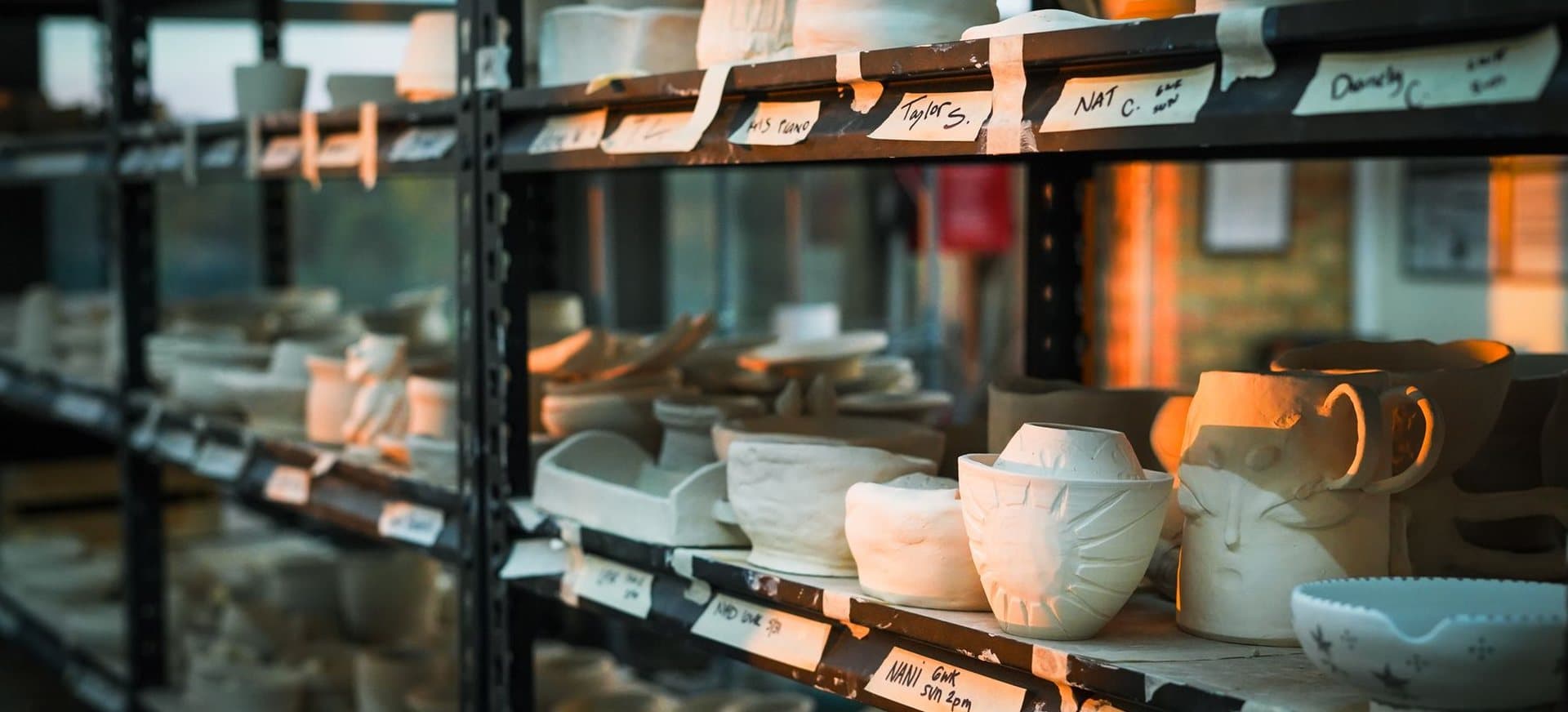 Rows of student pottery on studio drying racks