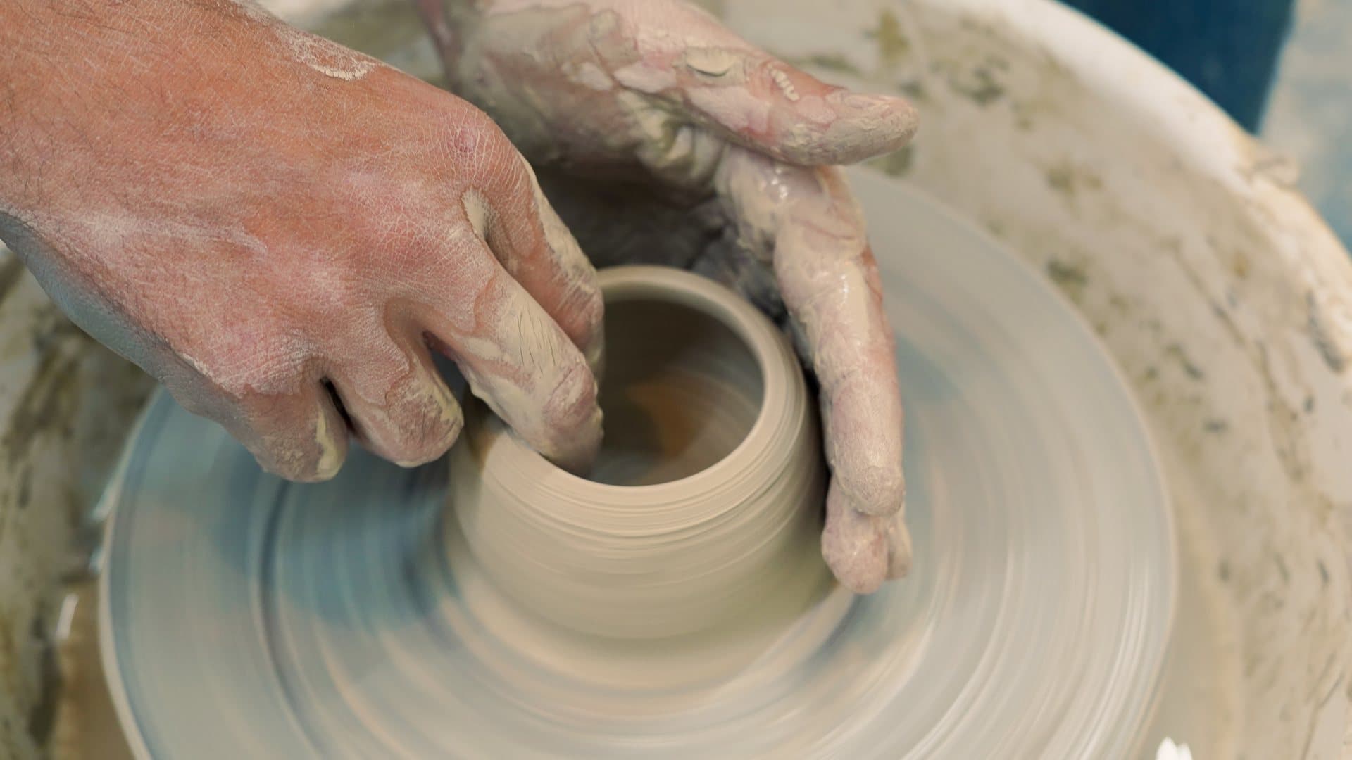 Hands throwing a pot on the pottery wheel