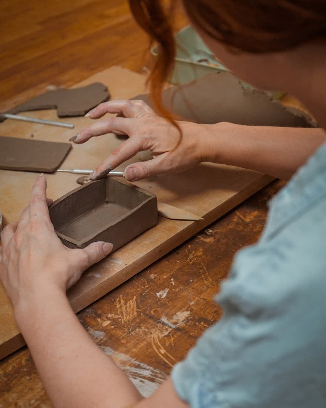 Hands shaping a wide matcha bowl on a worktable at The Pottery Loop