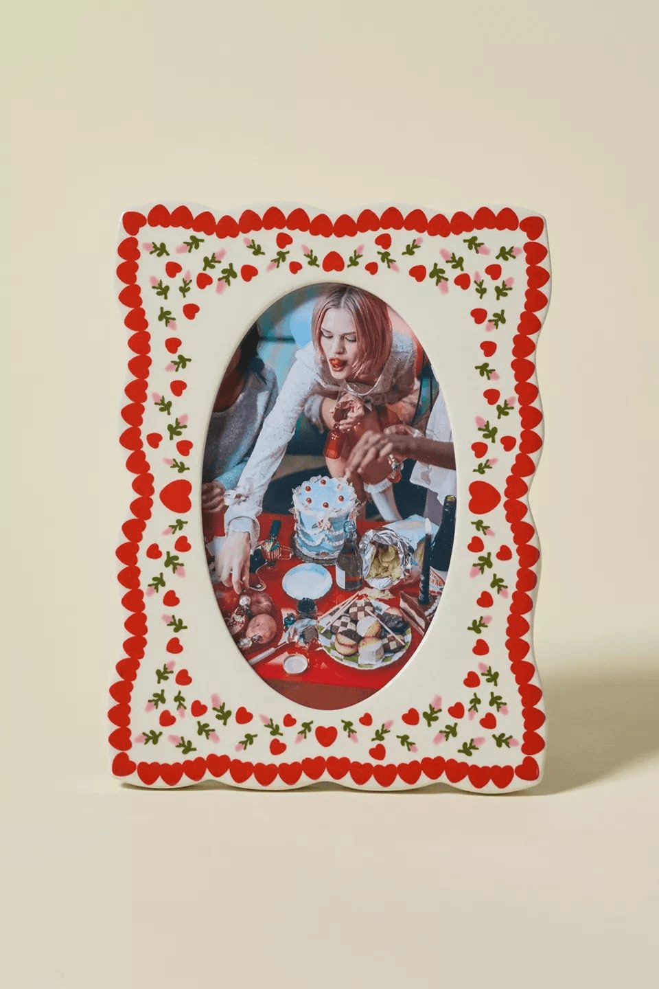 A scalloped ceramic photo frame painted with little red hearts