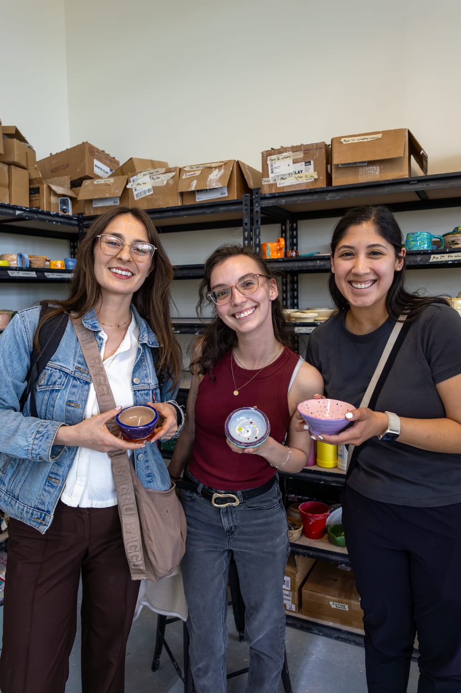 Three friends holding their glazed bowls
